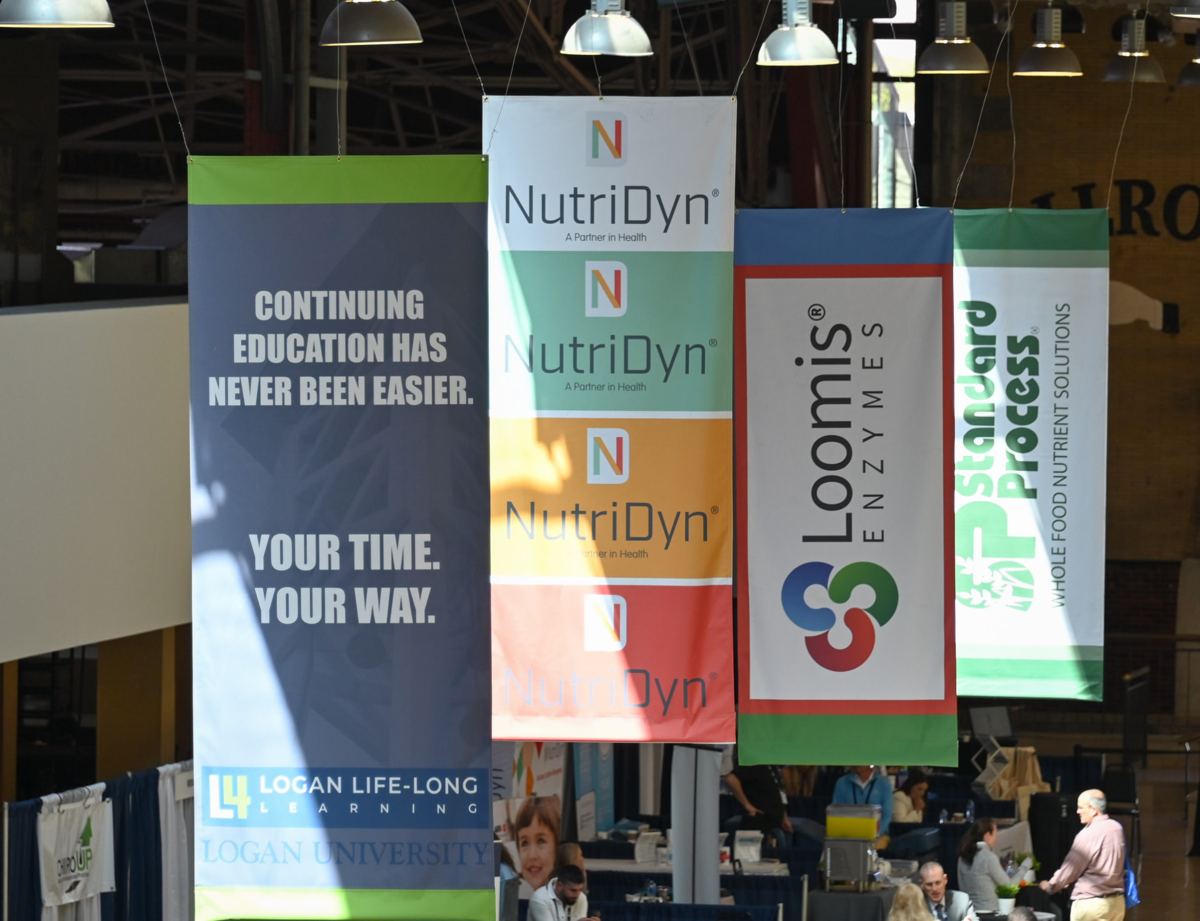 Logan Life-Long Learning banner hanging with sponsor banners above a continuing education exhibit hall
