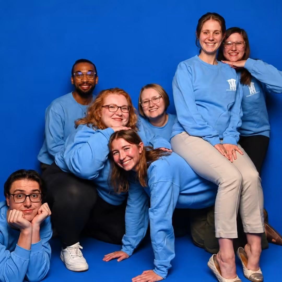 Logan University admissions team in matching light-blue sweatshirts posing together in front of a blue backdrop