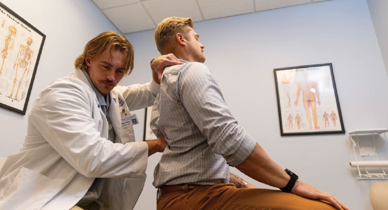 A Logan chiropractic student adjusting a patient in a treatment room