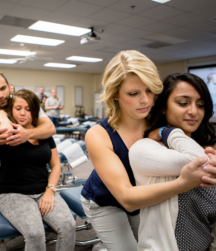 Logan students practising adjusting techniques on each other in a technique lab