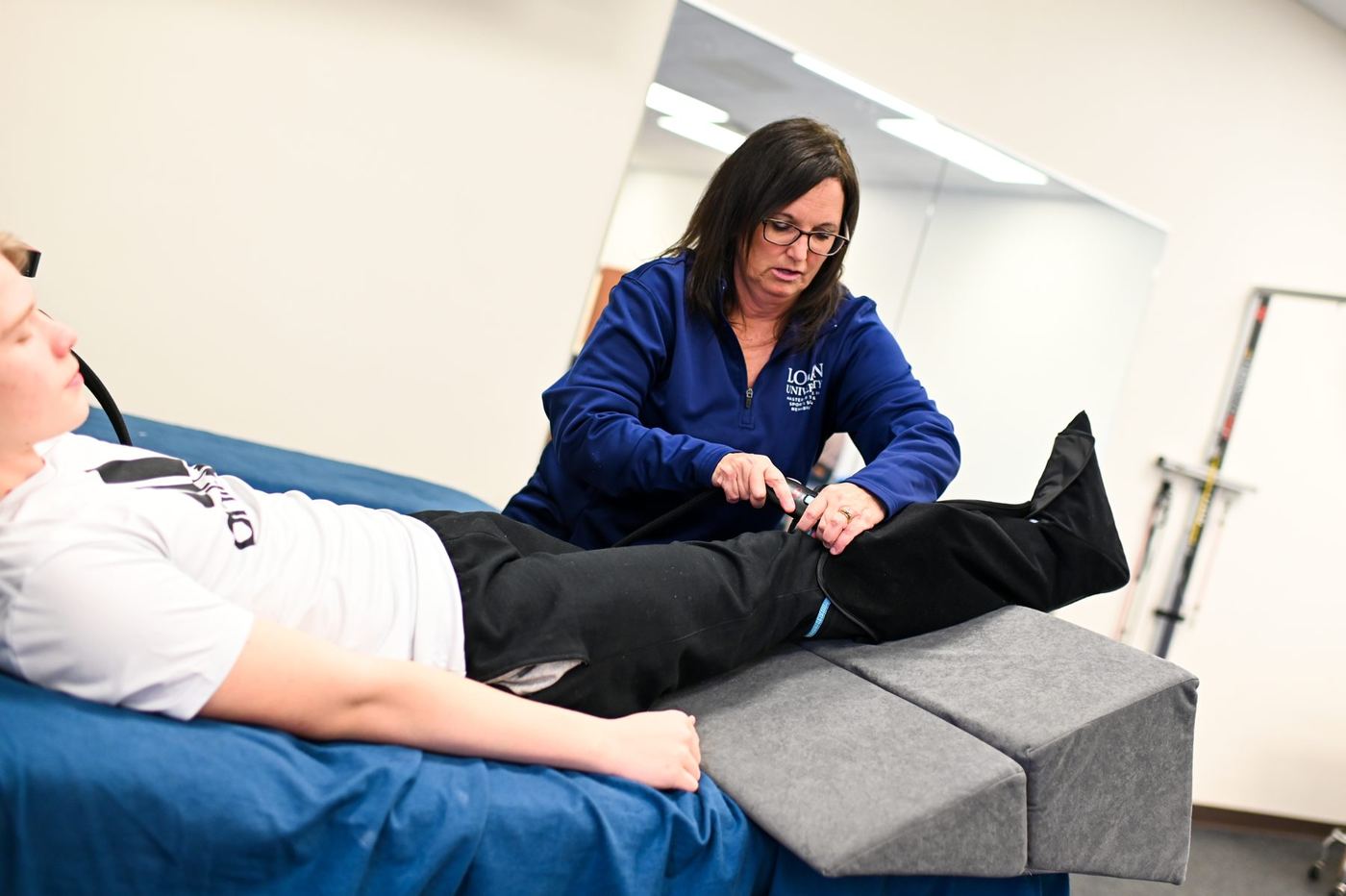 Logan clinician treats patient's leg on a medical bed, using foam blocks for support.