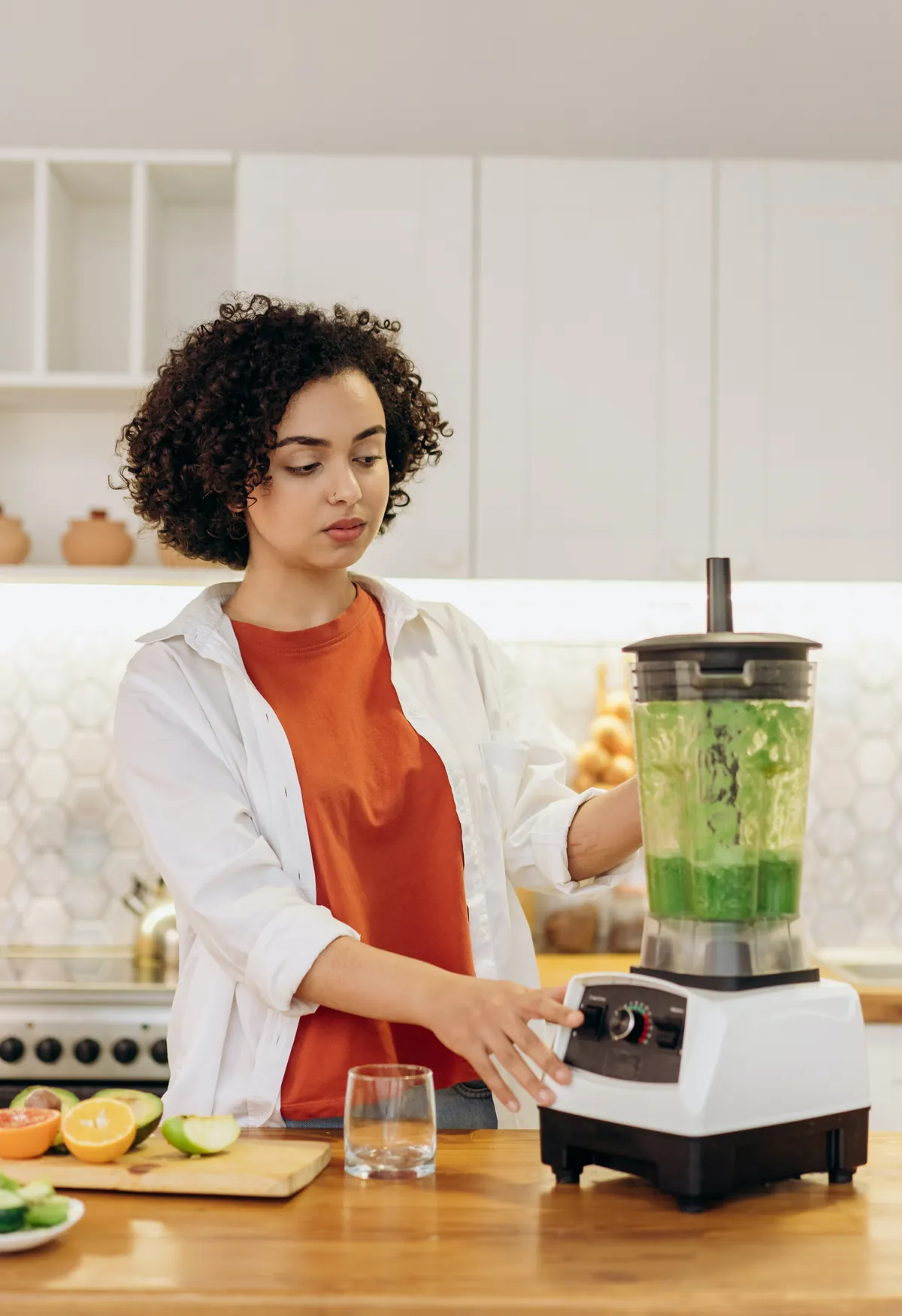 A woman makes a green smoothie in a blender as part of a nutrition masters program