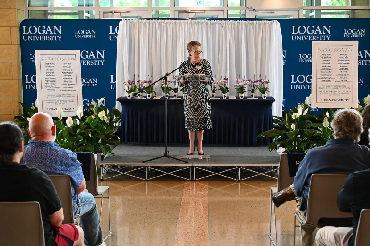 Speaker at the Logan University anatomical donor memorial ceremony, with tribute boards honoring donors