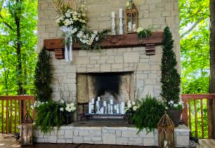 The pavilion's stone fireplace framed by greenery and floral arrangements