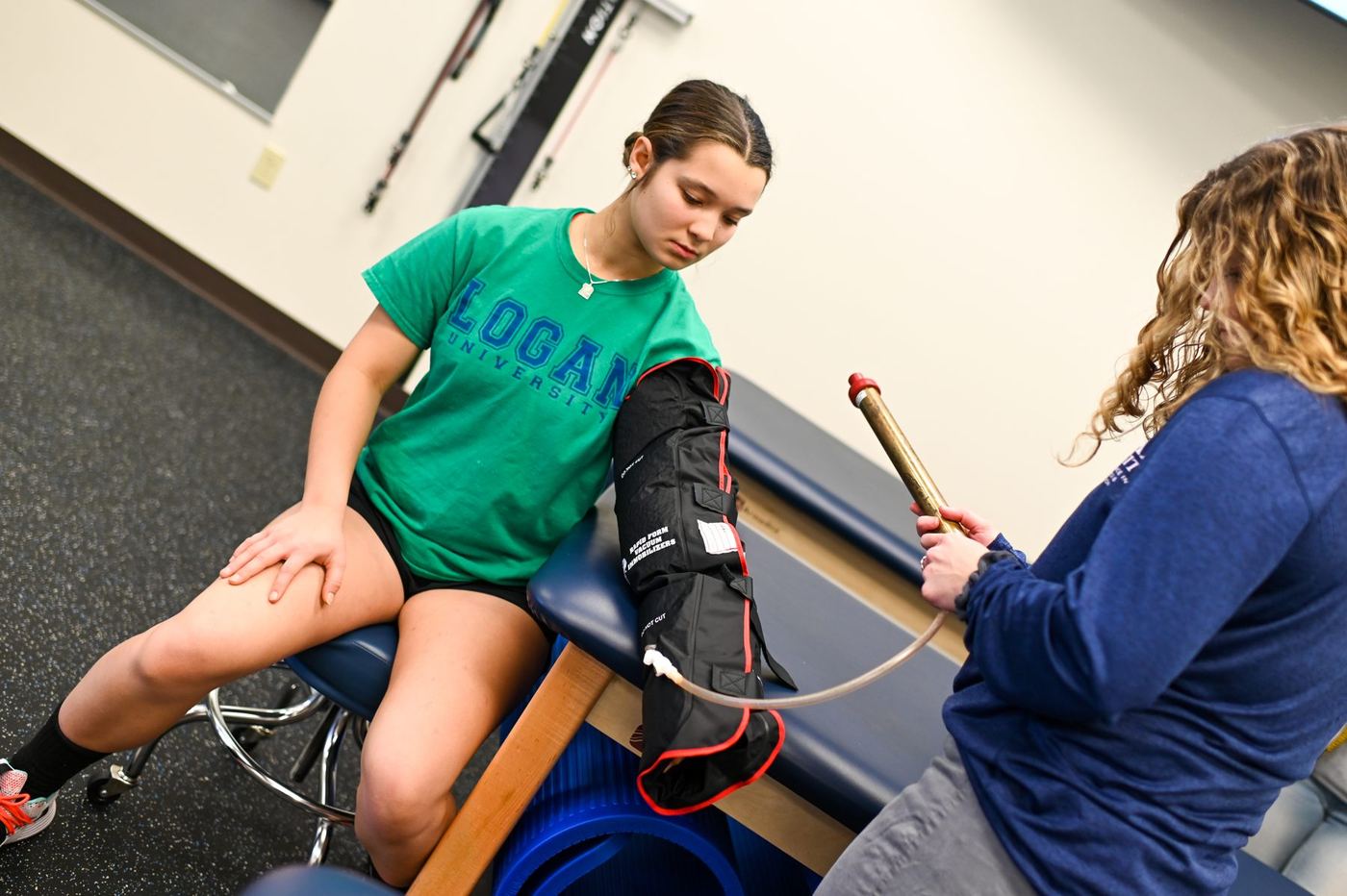 Person uses a vacuum pump on a student's leg in an immobilizer, demonstrating a clinical skill.