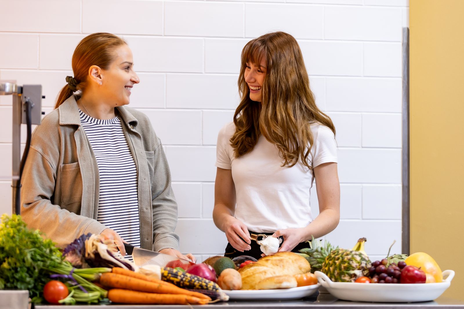Two students talk over fresh produce in Logan's teaching kitchen