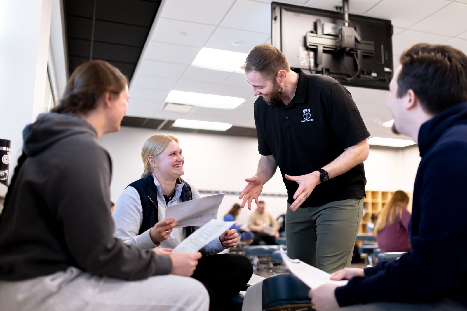 A Logan faculty member talks with students in a classroom