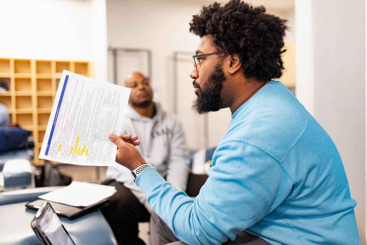 A Logan University student reviewing a patient history case sheet during a clinical skills class