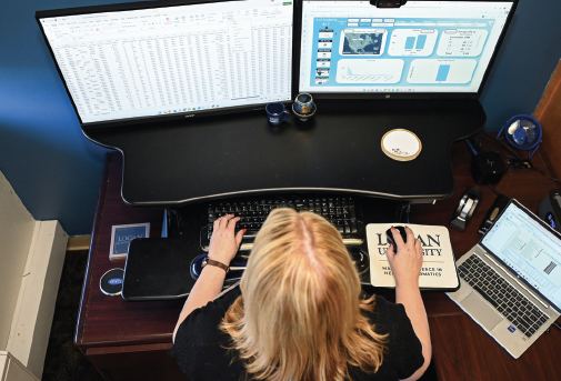 A Logan health informatics student reviewing health data on dual monitors