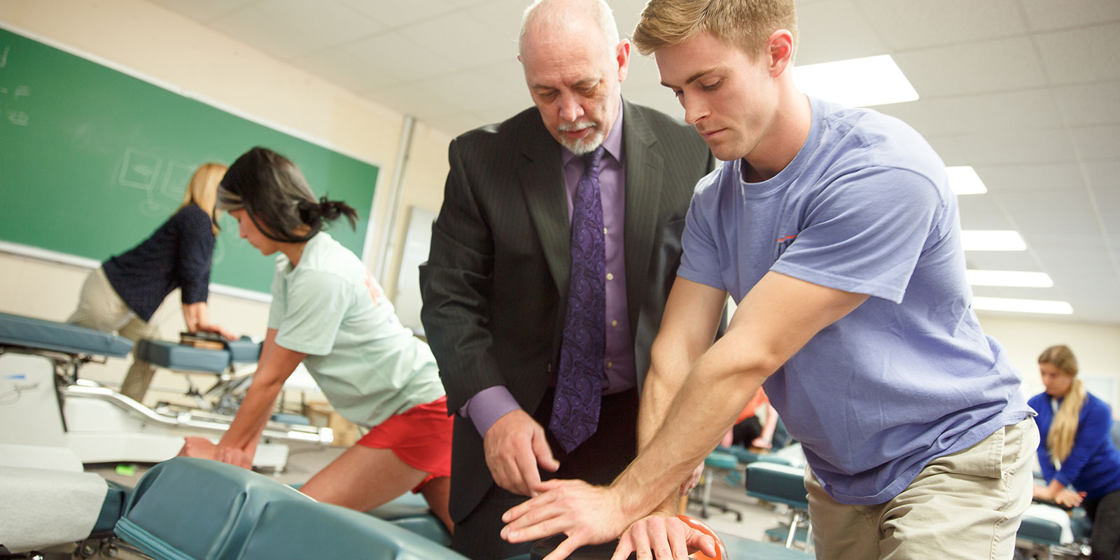 chiro-techniques-full-width Student working with teacher on chiropractic technique.