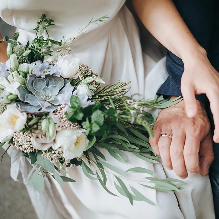 Close up of young couple holding hands.