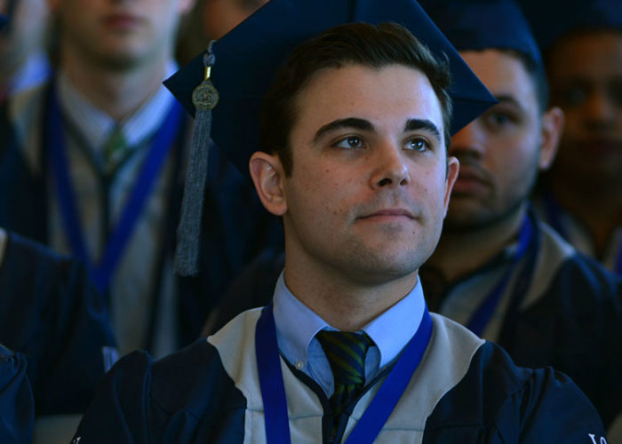 regalia-grid-large Male student sitting during graduation.