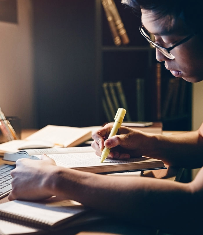 male student studying at night in front of a computer