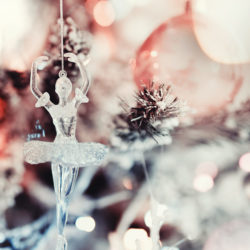 Glass ballerina ornament hanging on snow-dusted Christmas tree