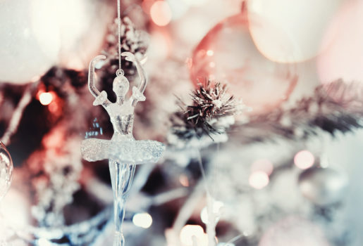 Glass ballerina ornament hanging on snow-dusted Christmas tree