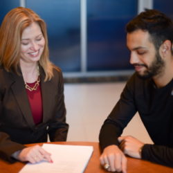 Dana Wehrli points to a piece of paper on a table as she meets with a student on campus