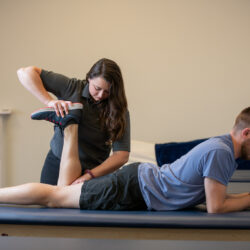 Logan University athletic training student works with a patient on a table.