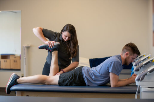 Logan University athletic training student works with a patient on a table.