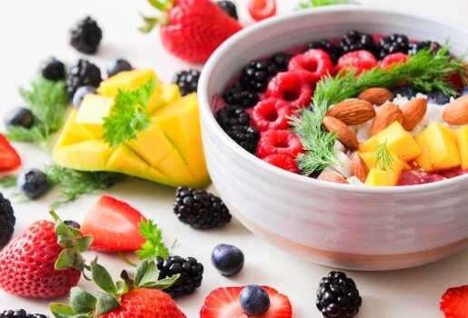 A bowl of fruit, nuts and vegetables sits on a table