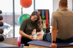 An athletic trainer wraps a bandage around an athlete's foot