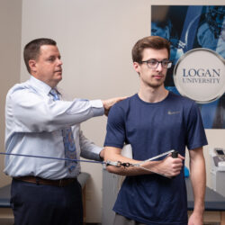 An athletic trainer touches the shoulder and elbow of an athlete